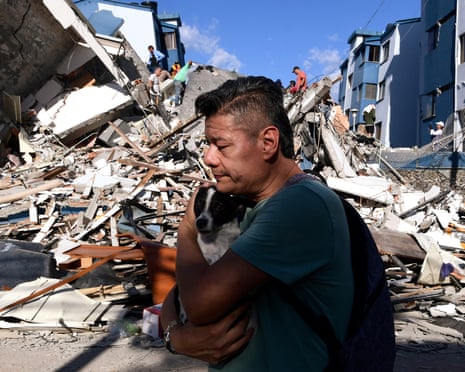 A man carries a dog as he walks past the rubble of a collapsed building in Pereira, western Colombia