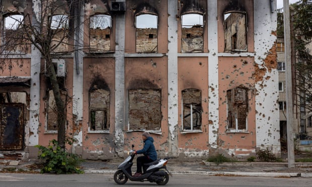 A woman rides past a destroyed building in Izium, Kharkiv region.