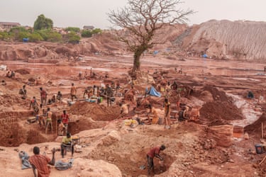 A landscape showing dozens of men digging in the red soil