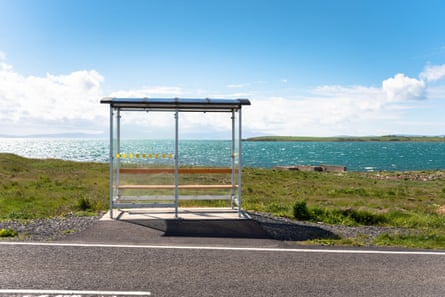 Bus stop on a sunny day with sea and distant land behind.