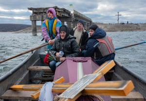 A woman sits in a boat crossing the Siverskyi Donets River in Kharkiv, Ukraine and transporting the coffin containing her dead son, a soldier who was killed in fighting during ther Russian invasion