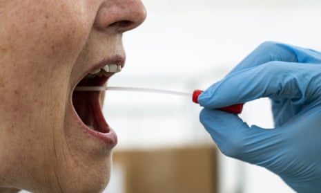 A medical worker performs a mouth swab on a patient in Copenhagen, Denmark