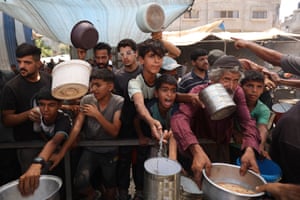 Palestinian boys and men hold out empty tins for hot food