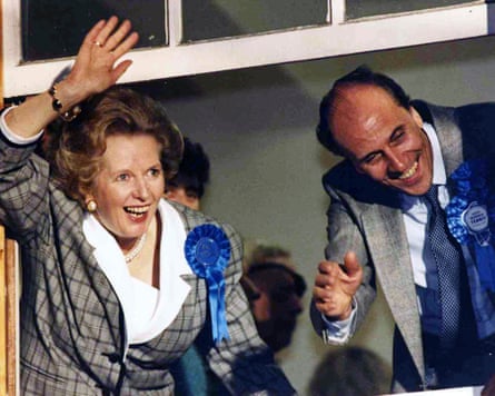 Margaret Thatcher and Norman Tebbit wave to supporters from a window at Conservative party headquarters, London, after election victory; they both have blue rosettes on their jackets.
