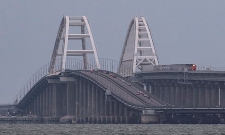 A passenger train and cars drive on the Kerch bridge after an explosion destroyed part of it