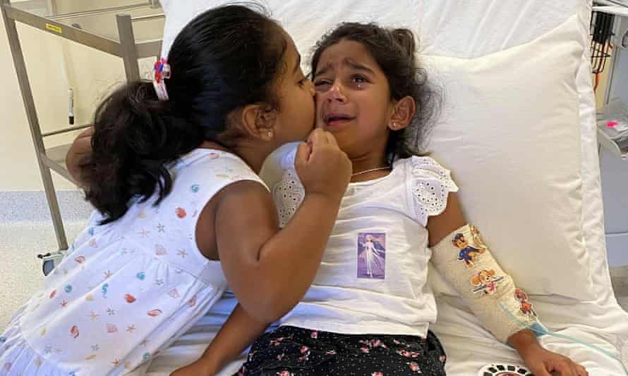 Tharnicaa, the youngest daughter of the ‘Biloela family’ is kissed by her elder sister in hospital