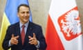 Radosław Sikorski gestures with both hands while speaking, standing in front of the Ukrainian and Polish flags next to each other