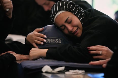 A woman cries as she hugs a press helmet over a coffin.