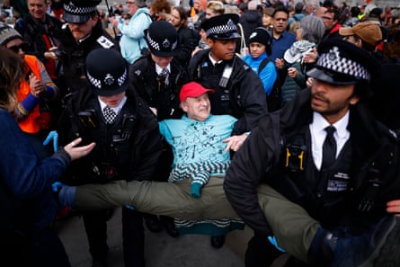 Police officers carry an elderly male protester at Palestine Action demonstration in Trafalgar Square