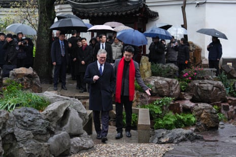 Keir Starmer walks with his team and local people with their umbrellas up during wet weather in Yuyuan Garden