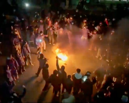 A large crowd of people around a fire in a street