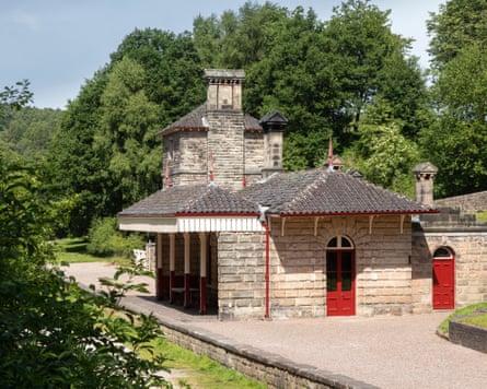 A small station building with red doors on a disused platform