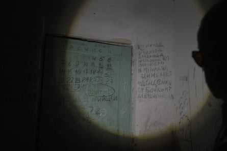 A long list of names written on a dirty white wall next to a green door
