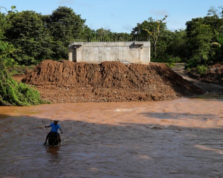 A farmer wades through the Indio River on horseback near a concrete structure in Panama