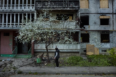 Woman walking in a grey, desolate street with a blossom tree in flower
