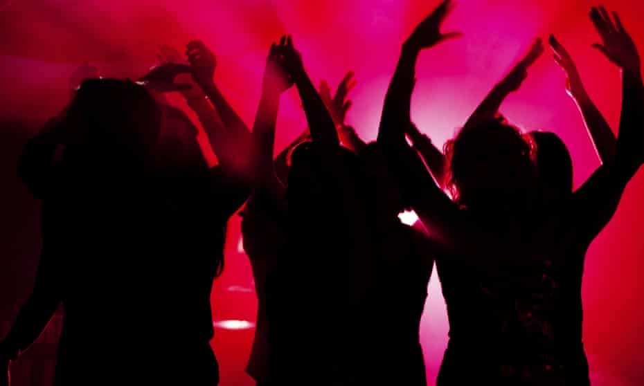 Silhouette of people dancing in club with lightshow