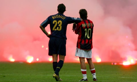 Marco Materazzi and Rui Costa watch on as flares settle on the pitch at San Siro in 2005.