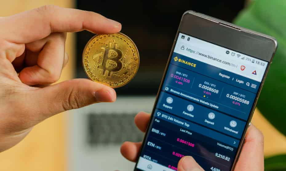 a bitcoin coin and Binance app on a smartphone