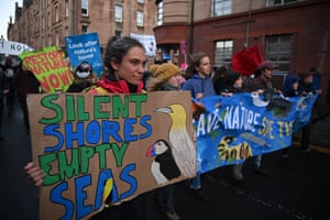 protesters carry a placard saying “Silent Shores Empty Seas”