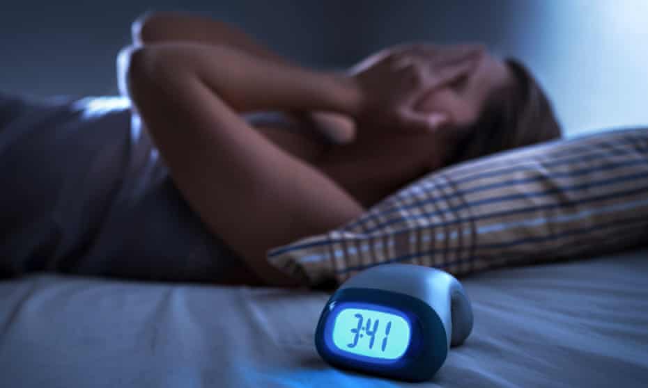 Sleepless woman with alarm clock on the bed