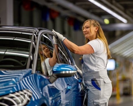 A Volkswagen employee completes a quality control inspection on an electric vehicle