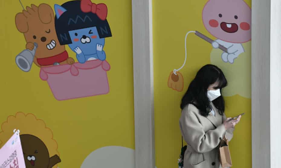 A woman wearing a face mask uses her phone in a railway station in Seoul 
