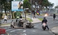 FRANCE-OVERSEAS-NEW CALEDONIA-POLITICS-UNREST<br>People walk next to a burnt-out car while a man (C) holds a flag of the Socialist Kanak National Liberation Front (FLNKS) after a supermarket was looted and shops vandalised in the N'Gea district of Noumea, on May 14, 2024. New Caledonia's high commissioner said on May 14 that shots had been fired at security forces during a night of riots in the French Pacific territory that saw vehicles torched and shops looted. Authorities in the French-run archipelago announced a night-time curfew Tuesday and a ban on public gatherings after protests against proposed voting reforms that have angered separatists. (Photo by Delphine Mayeur / AFP) (Photo by DELPHINE MAYEUR/AFP via Getty Images)
