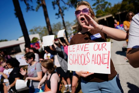 a woman with a sign reading ‘leave our schools alone’