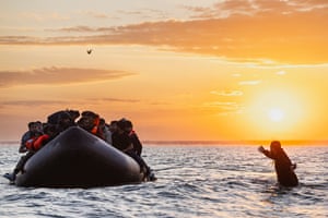 A man tries to board an inflatable dinghy filled with people