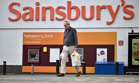 A shopper walks away from a Sainsbury's supermarket