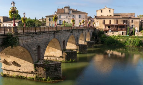 An arched roman bridge to a pretty town on a sunny day.