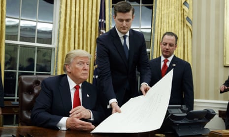 The then White House staff secretary, Rob Porter, center, hands Donald Trump a document in the Oval Office in January 2017, as the then chief of staff Reince Priebus, right, watches.