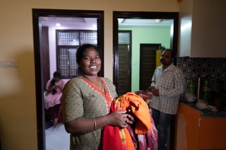 Abha Kujur holds clothes to be ironed as her older daughter, Neha, and husband look on.