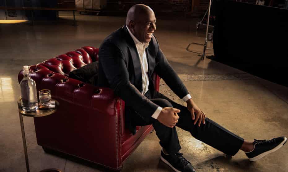 Earvin ‘Magic’ Johnson leaning forward in a red leather armchair and laughing