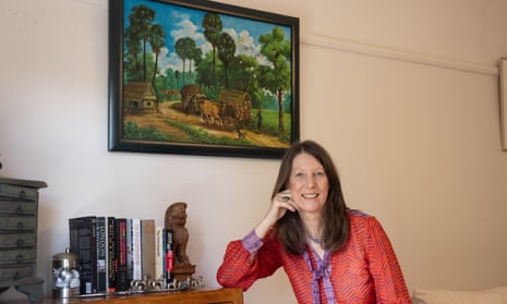Clare Arthurs, a former BBC journalist, sits in front of an artwork she bought from Cambodian artisit Vann Nath