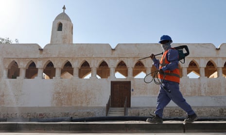 A worker walks past a traditional structure on the seafront in Doha during renovation work ahead of the 2022 World Cup