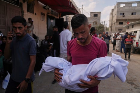 A relative carries the body of a 2-year-old Palestinian child, Malek Al-Zaqzouq, who was killed in an Israeli military strike.