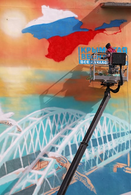 A worker paints the words that read “Crimean Spring” on a mural on the wall of a building in Simferopol, Crimea.