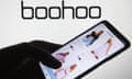 Boohoo website on a mobile phone with the Boohoo logo in the background.