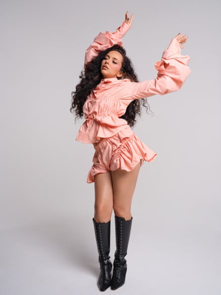 Jade wearing a pale-tangerine, rouched shirt and shorts set and pair of knee-length black boots