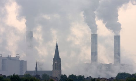 A Catholic church spire against smoky coal power plants in North Rhine-Westphalia, Germany