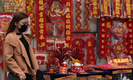 A woman walks past notes containing Chinese New Year calligraphy and decorations displayed on a street to celebrate the Lunar New Year on 14 January.