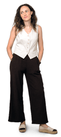 Caterina, white with mid-length brown hair, stands with hands in pockets, wearing cream waistcoat, black trousers and espadrilles
