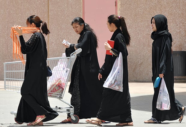 Filipina maids wearing black cloaks carrying shopping bags in Riyadh.