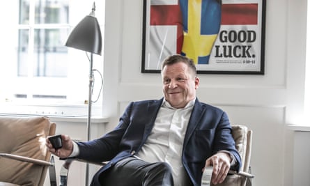 Christen Ager-Hanssen in London, April 2019: he is a fair-haired, sturdily built middle-aged man, photographed looking relaxed in a chrome-framed, pale leather armchair next to a metal reading lamp and in front of a picture of Scandinavian flags which bears the words ‘good luck’. He is holding an espresso cup and is wearing a blue jacket and white shirt with open collar.