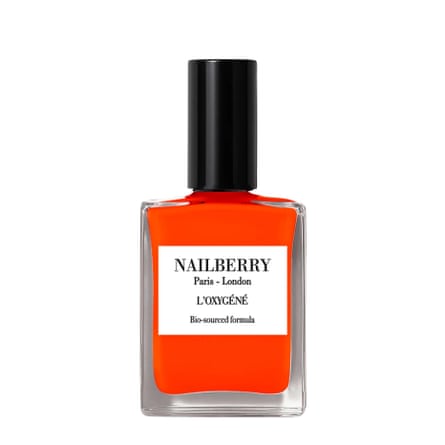 A bottle of Nailberry L’Oxygéné Nail Polish. The colour is bright red-orange and is called “Joyful”/. The bottle is squared and clear to see the varnish colour and the lid is a black screw top.