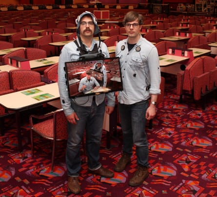 Two nerdy looking men, one with a laptop around his neck