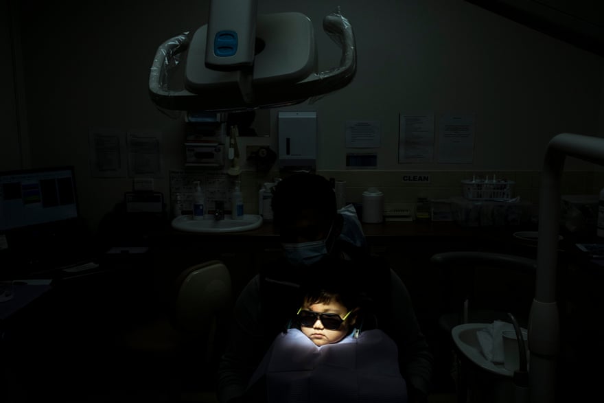 Young Daniel sits on his father lap as he prepares to have fillings inserted at the local dentist.