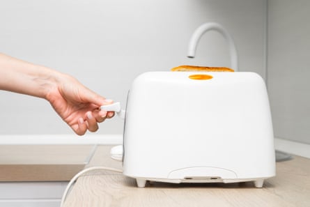 A person pushing the lever on a toaster