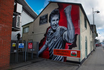A portrait of Wrexham legend Joey Jones looks down from the side of the Turf pub, located directly outside Wrexham’s Cae Ras ground.